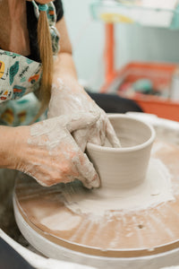 hands making a bowl from clay on a pottery wheel